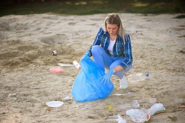 Junger Freiwilliger, der Plastikflaschen am Strand nahe dem Park aufhebt.