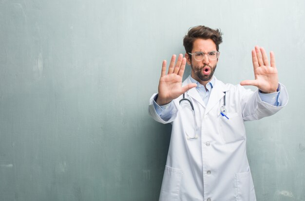 Foto junger freundlicher doktormann gegen eine schmutzwand mit einem kopienraum ernst und bestimmt