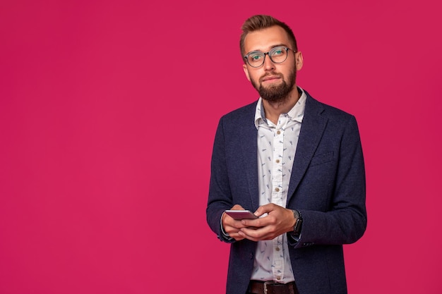 Junger fröhlicher Anwalt oder Geschäftsmann steht auf dem rosa Hintergrund und lächelt und liest gute neue...