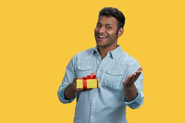 Junger fröhlicher arabischer Mann mit einer gelben Geschenkbox