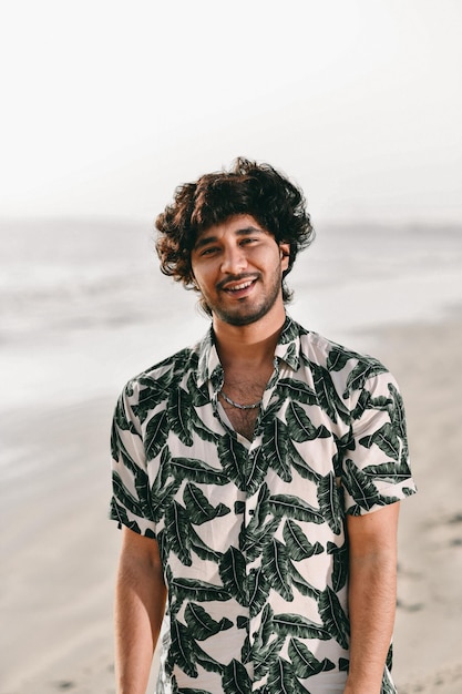 junger fröhlicher glücklicher Mann am Strand indisches pakistanisches Modell