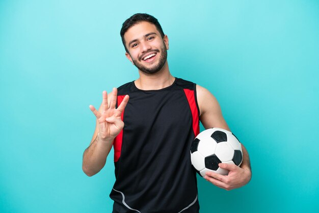 Junger Fußballspieler Brasilianer isoliert auf blauem Hintergrund glücklich und zählt vier mit den Fingern