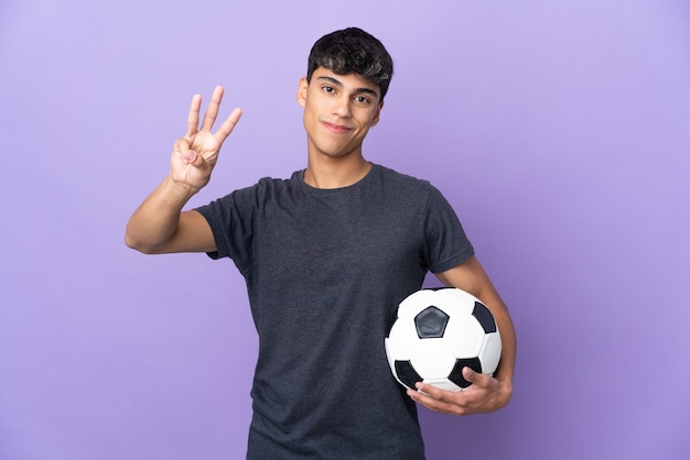 Junger Fußballspieler Mann über lila glücklich und zählt drei mit den Fingern