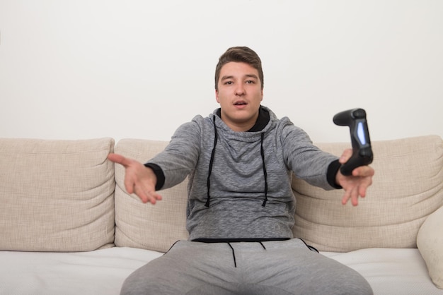 Junger Gamer sitzt auf dem Sofa und spielt zu Hause Videospiele