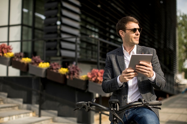 Junger Geschäftsmann auf dem E-Bike mit digitalem Tablett