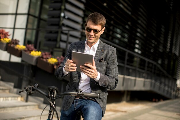 Junger Geschäftsmann auf dem E-Bike mit digitalem Tablett