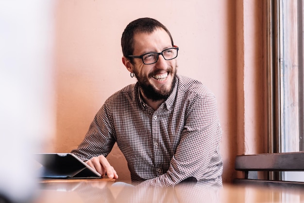 Junger Geschäftsmann, der an seinem Tablet in einem Café-Shop arbeitet