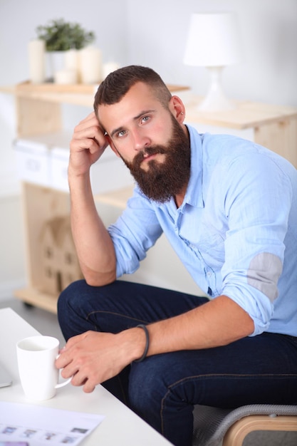 Junger Geschäftsmann, der auf Stuhl im Büro sitzt