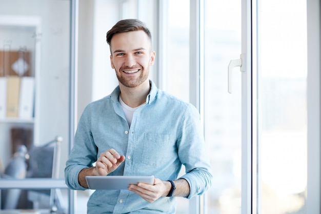 Junger Geschäftsmann, der durch Fenster aufwirft