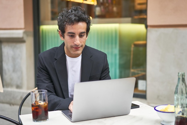 Junger Geschäftsmann, der hart an der Arbeit mit seinem Laptop arbeitet und sich darauf konzentriert, seine Ziele zu erreichen