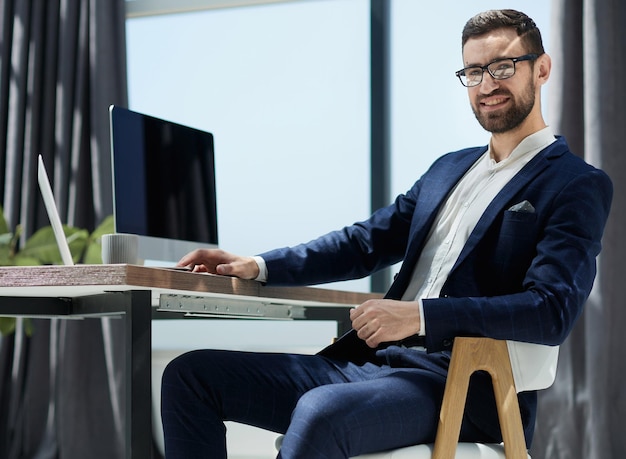 Junger Geschäftsmann, der im Büro arbeitet und am Schreibtisch sitzt