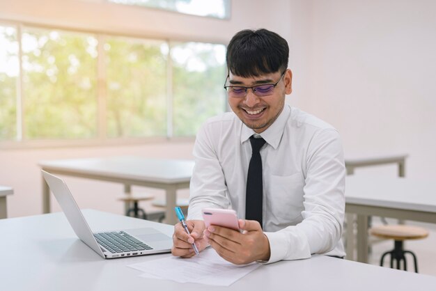 Foto junger geschäftsmann, der im büro mit laptop, mobile und dokumenten arbeitet