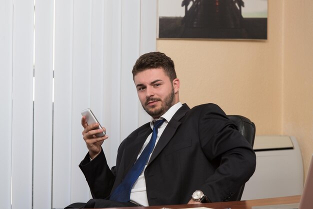 Junger Geschäftsmann, der in seinem Büro arbeitet, während er am Telefon spricht