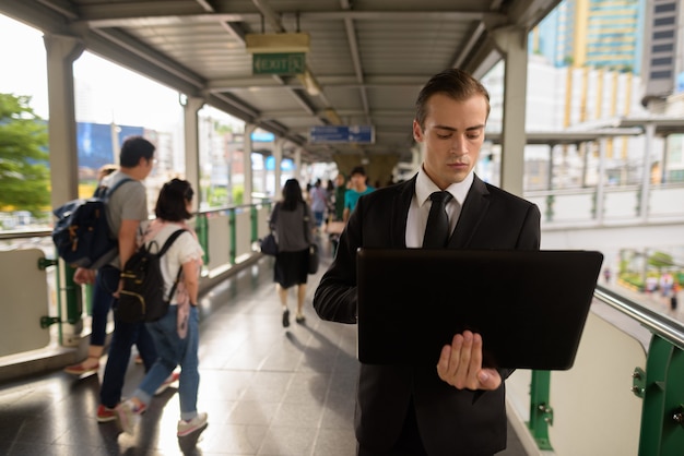 Junger Geschäftsmann, der Laptop-Computer in der Stadt benutzt