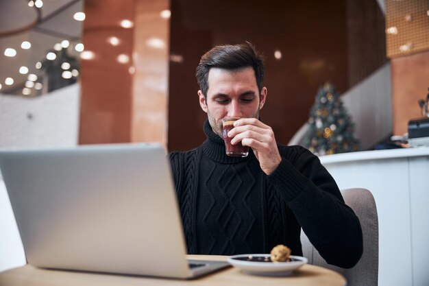 Junger Geschäftsmann, der mit einer Tasse Kaffee im Internet arbeitet