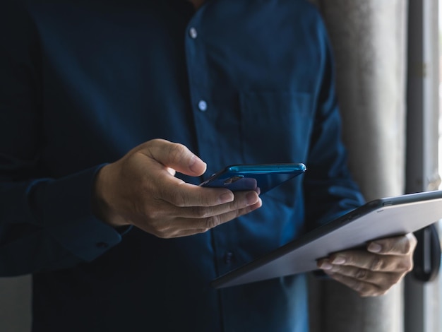 Junger Geschäftsmann, der mit modernen Geräten, digitalen Tablet-Computern und Mobiltelefonen arbeitet