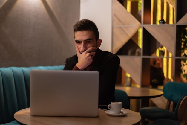 Junger Geschäftsmann, der nachts an einem Laptop in seinem Büro arbeitet