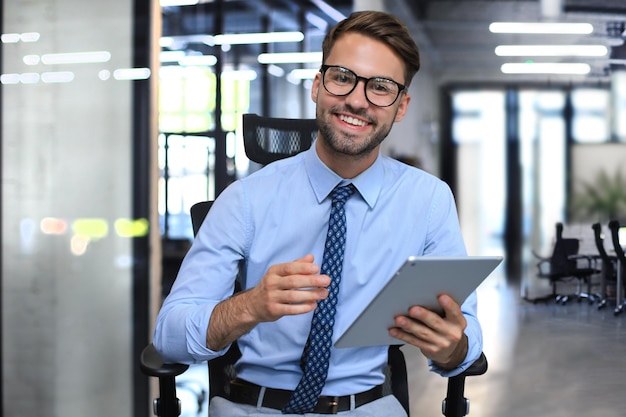 Junger Geschäftsmann, der seine Tablette im Büro verwendet