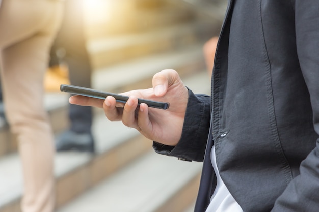 junger Geschäftsmann, der unscharfen Hintergrund des beweglichen Smartphone verwendet