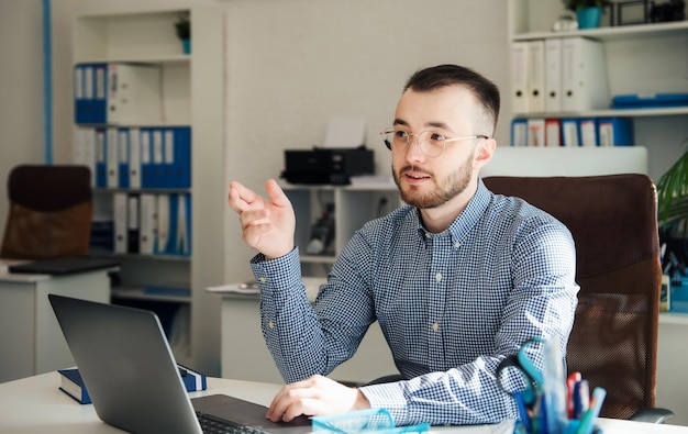 Junger Geschäftsmann im Hemd, der an seinem Laptop in einem Büro arbeitet