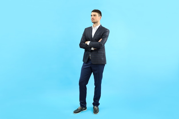 Junger Geschäftsmann im klassischen Anzug auf blauem Hintergrund.