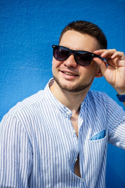 Junger Geschäftsmann in blauem Hemd und schwarzer Brille auf blauem Hintergrund