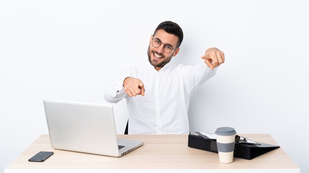 Junger Geschäftsmann in einem Arbeitsplatz zeigt Finger auf Sie beim Lächeln