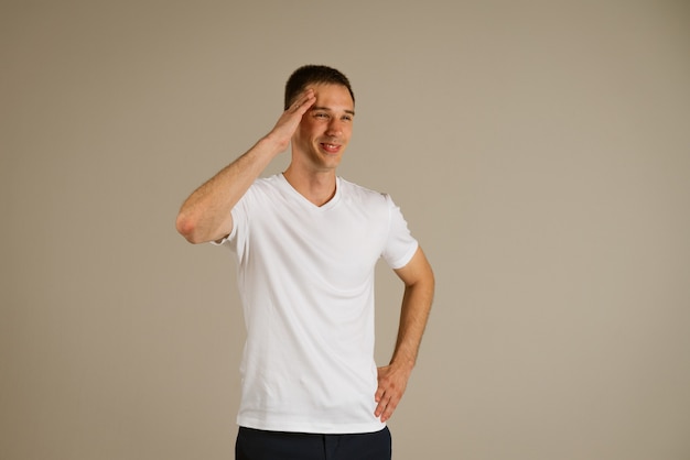 Junger Geschäftsmann in einem weißen T-Shirt gestikulierend mit seinen Händen auf einer hellen Wand