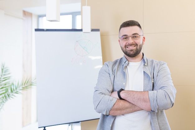 junger Geschäftsmann in Freizeitkleidung Online-Meeting-Präsentation oder Training unter Verwendung einer Laptop-Webcam und eines Flipcharts mit Markern