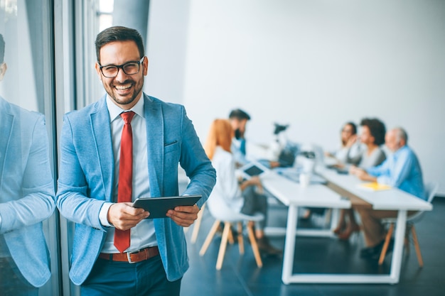 Junger Geschäftsmann mit digitaler Tablette im Büro