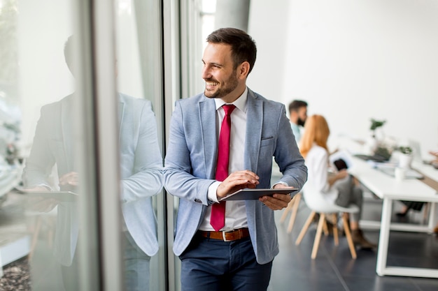 Junger Geschäftsmann mit digitaler Tablette im Büro