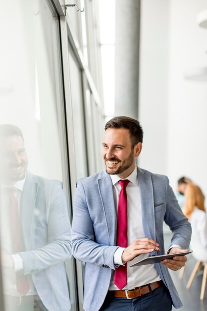 Junger Geschäftsmann mit digitaler Tablette im Büro