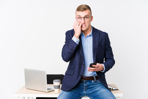 Junger Geschäftsmann mit einem Laptop, der Fingernägel beißt, nervös und sehr ängstlich.