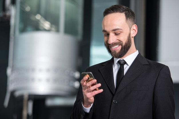 Junger Geschäftsmann mit Handy im modernen Büro.