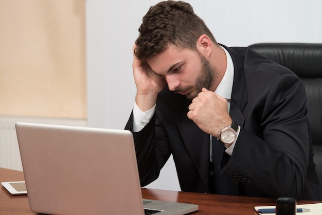 Junger Geschäftsmann mit Problemen und Stress im Büro