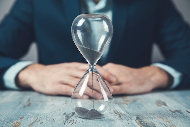 Junger Geschäftsmann mit Sanduhr auf Tisch