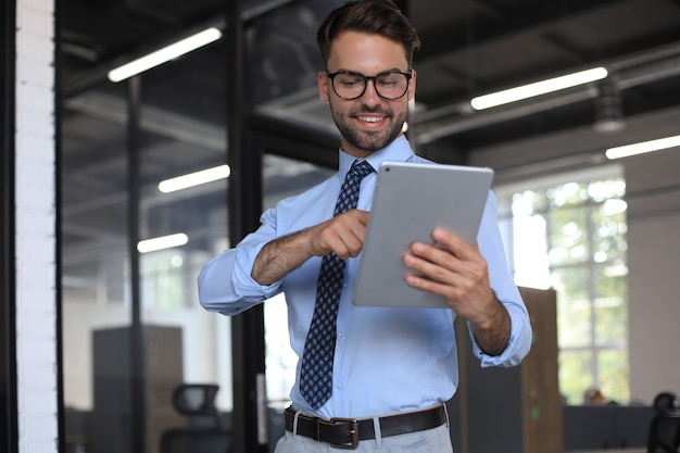 Junger Geschäftsmann mit seinem Tablet im Büro.