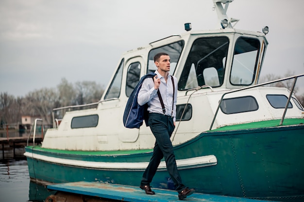 Foto junger geschäftsmann steht auf pier gegen bootshintergrund