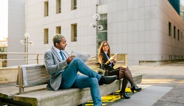 Junger Geschäftsmann und Frau sitzen auf der Bank und unterhalten sich