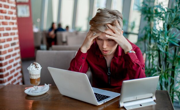 Junger gestresster Mann, der in einem Café arbeitet