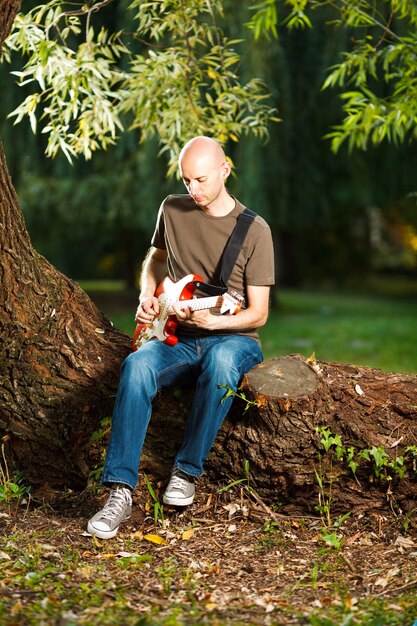 Junger Gitarrist, der in einer wunderschönen Naturumgebung Gitarre spielt