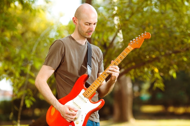 Junger Gitarrist, der in einer wunderschönen Naturumgebung Gitarre spielt