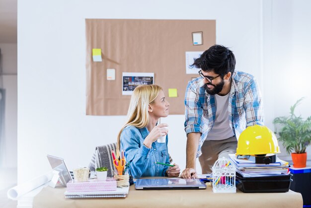 Junger glücklicher Designer in ihrem Büro, der über das Geschäft spricht.