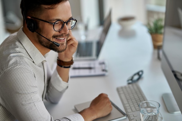 Junger, glücklicher Kundendienstmitarbeiter, der im Call Center arbeitet