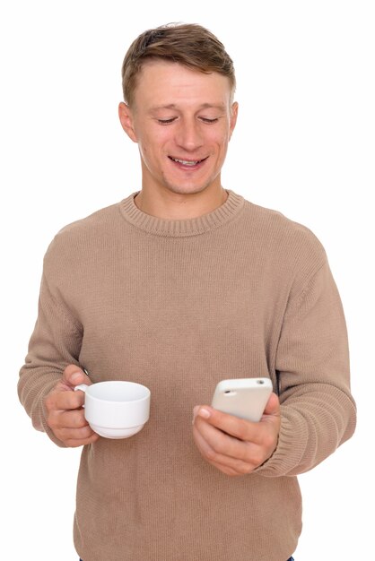 junger glücklicher Mann, der Handy beim Kaffeetrinken verwendet