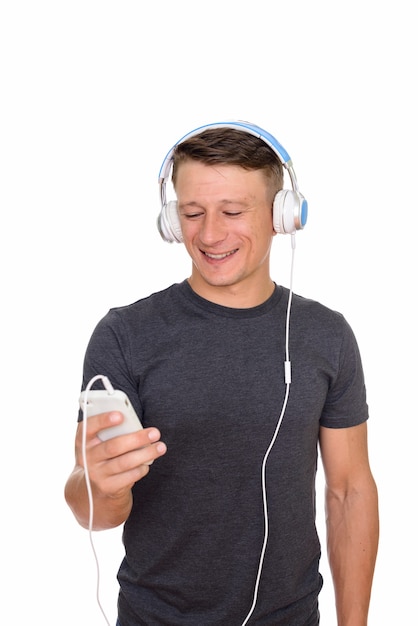 junger glücklicher Mann, der Handy und Kopfhörer benutzt