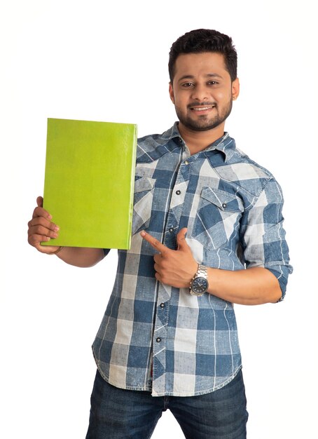Junger glücklicher Mann, der mit dem Buch auf weißem Hintergrund hält und aufwirft