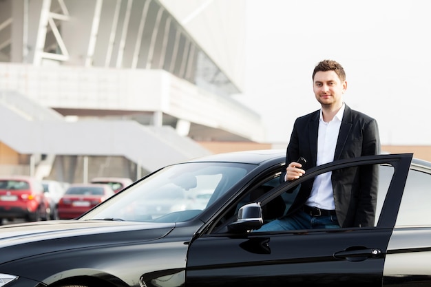 Junger glücklicher Mann kaufte neues modernes Auto