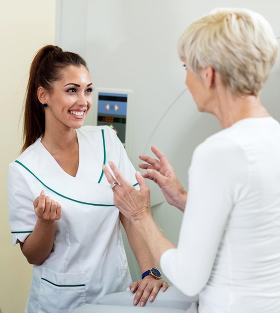 Junger, glücklicher Radiologe, der vor der CT-Untersuchung in der Klinik mit einem Patienten kommuniziert