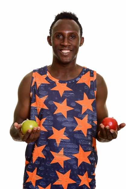 Junger glücklicher Schwarzafrikaner, der lächelt, während er grünen und roten Apfel hält